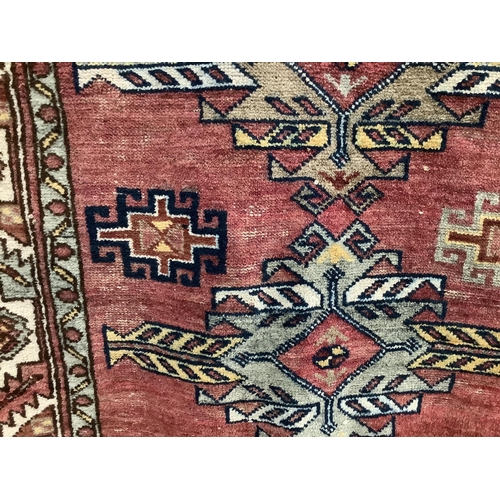 1104 - A Caucasian style red ground rug, 210 x 120cm. Condition - fair