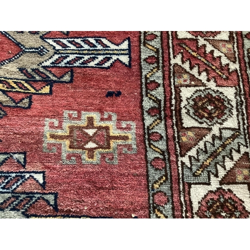 1104 - A Caucasian style red ground rug, 210 x 120cm. Condition - fair