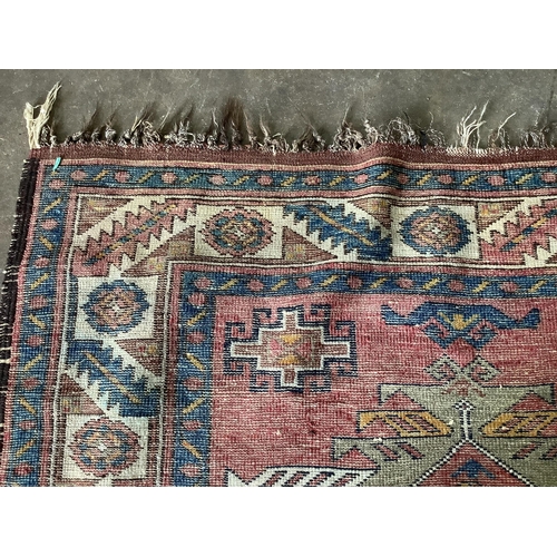 1104 - A Caucasian style red ground rug, 210 x 120cm. Condition - fair
