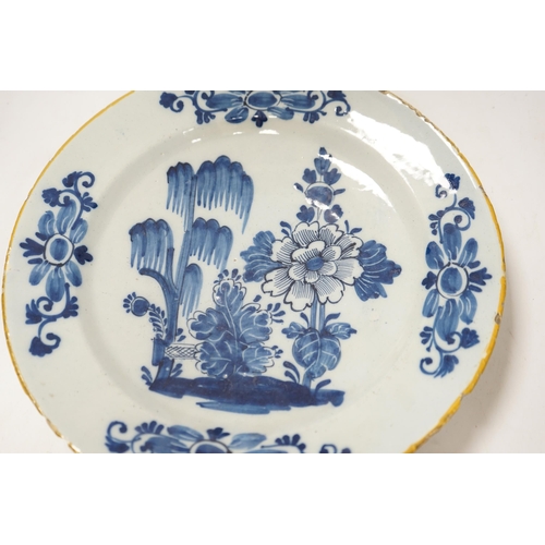 1351 - An 18th century delft blue and white dish, painted with a stylised peony and willow tree, 32cm diame... 