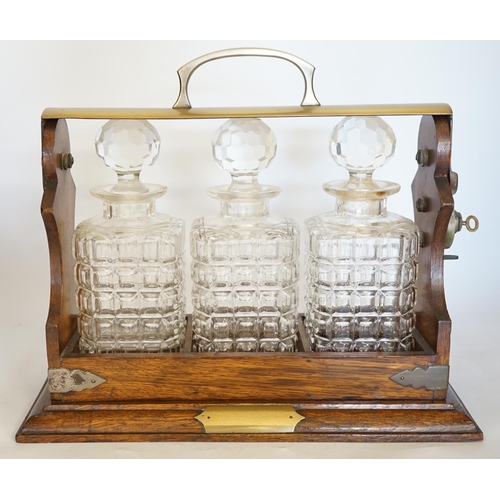 1384 - A brass mounted oak three decanter tantalus, 37cm wide. Condition - fair to good