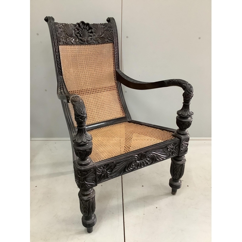85 - A 19th century Anglo-Indian carved ebony library armchair, with a caned seat and back, width 60cm, d... 
