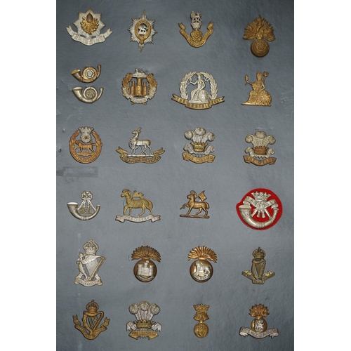 1385 - A collection of fifty-eight military cap badges, plus a few shoulder titles, mounted on four boards ... 