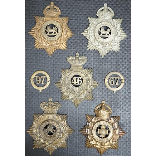 1386 - Five military helmet plates and two other centre badges mounted on a board, including; the Royal Lan... 