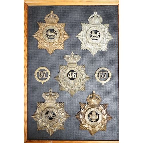 1386 - Five military helmet plates and two other centre badges mounted on a board, including; the Royal Lan... 