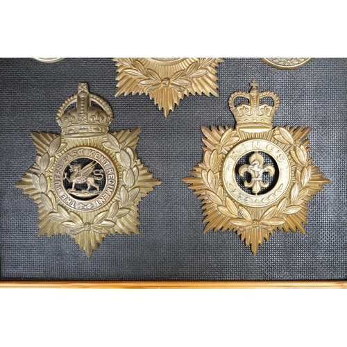 1388 - Five military helmet plates and two other centre badges, mounted on a board including; the Essex Reg... 