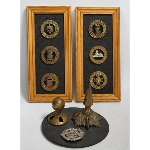 1389 - Six military helmet plates mounted on two boards, together with two helmet spikes and a cap badge, i... 