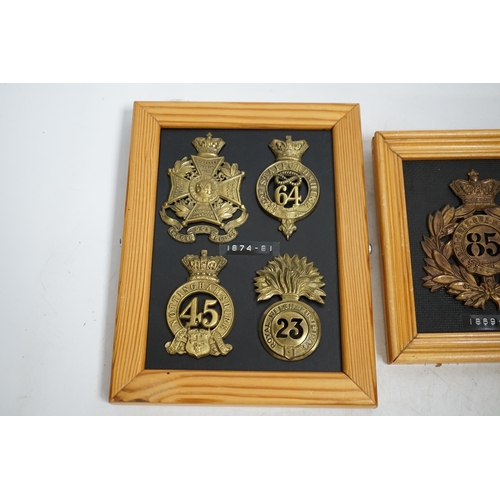 1390 - Five military helmet and shako plates mounted on two boards, including; the Nottinghamshire Regiment... 