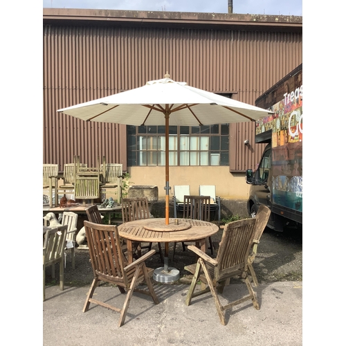 1041 - A circular weathered teak garden table with lazy Susan, diameter 150cm, height 75cm, a crank parasol... 