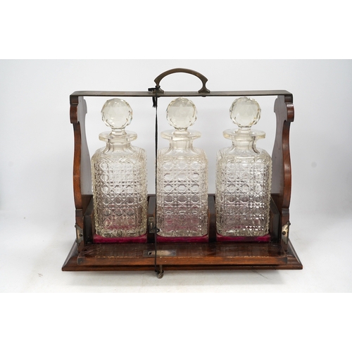 1324 - A three bottle tantalus with key, 38cm wide. Condition - fair, chipping to the stoppers