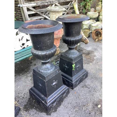 148 - A pair of Victorian style black painted cast iron campana shaped garden urns, on square plinths, dia... 