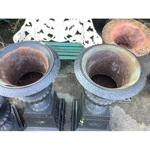 148 - A pair of Victorian style black painted cast iron campana shaped garden urns, on square plinths, dia... 