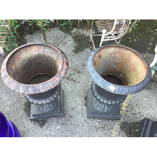 153 - A pair of Victorian style black painted cast iron campana shaped garden urns, on square plinths, dia... 