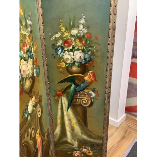 166 - An early 20th century painted canvas three fold dressing screen decorated with parrots among vases o... 