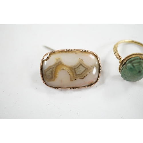 910 - An antique yellow metal 'Scarab' ring and a banded agate set brooch. Condition - poor to fair