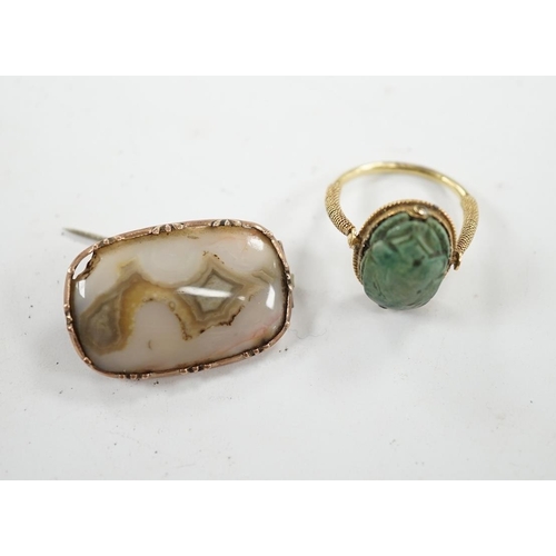 910 - An antique yellow metal 'Scarab' ring and a banded agate set brooch. Condition - poor to fair