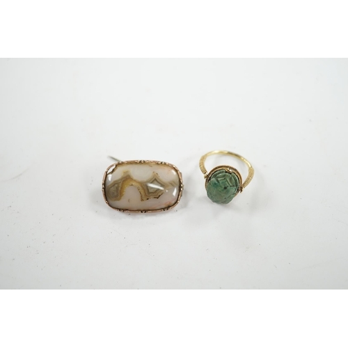 910 - An antique yellow metal 'Scarab' ring and a banded agate set brooch. Condition - poor to fair