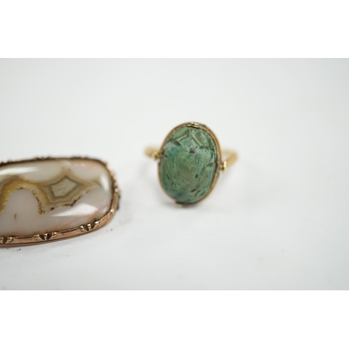 910 - An antique yellow metal 'Scarab' ring and a banded agate set brooch. Condition - poor to fair