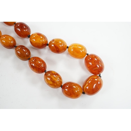 922 - A single strand graduated oval amber bead necklace, 76cm, gross weight 107 grams. Condition - poor... 