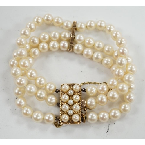 943 - A triple strand cultured pearl necklace, with 9ct and cultured pearl clasp and spacer, 18cm. Conditi... 