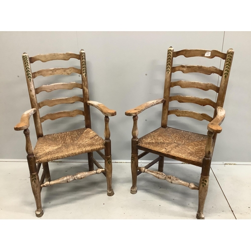 60 - A pair of 19th century Provincial fruitwood rush seated ladder back elbow chairs, later painted, wid... 