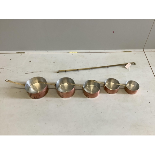 73 - A graduated set of five circular copper pans with brass hanging rail, largest diameter 20cm. Conditi... 