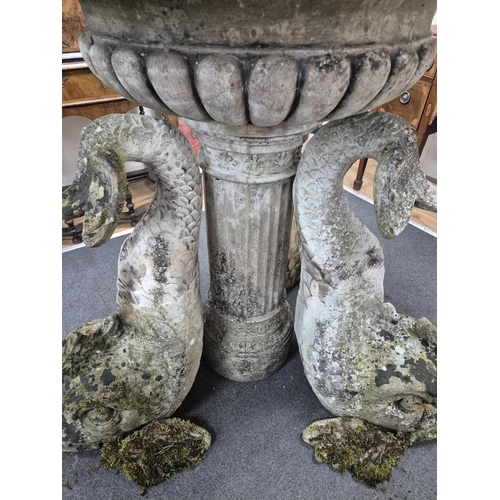 18 - A reconstituted stone bird bath with central bowl and dolphin brackets, on a circular plinth, 136cm ... 