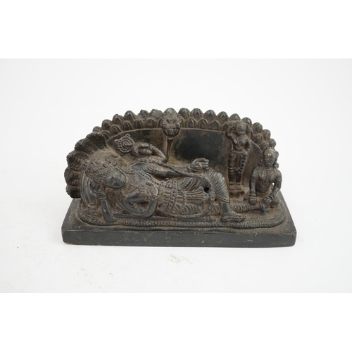 28 - An Indian basalt reclining figure of Shiva, probably Kakatiya period, 12th century A.D, the reclinin... 