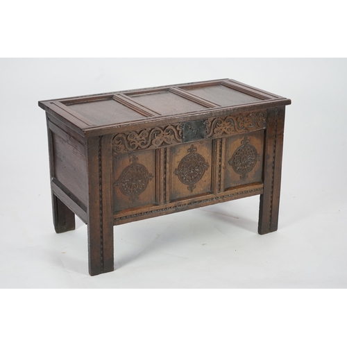 51 - A 17th century oak coffer with triple panelled top, candle box and rosette carved front, 95cm wide, ... 