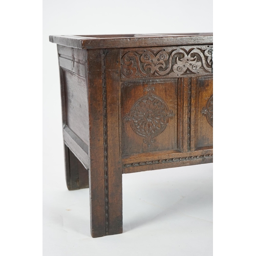 51 - A 17th century oak coffer with triple panelled top, candle box and rosette carved front, 95cm wide, ... 