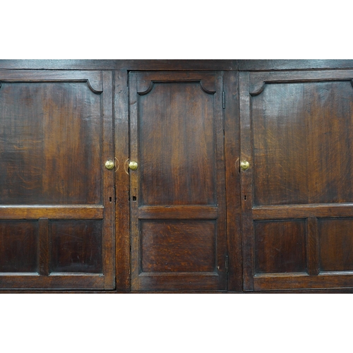 7 - A mid 18th century oak press cupboard with moulded cornice and three panelled doors over three dummy... 