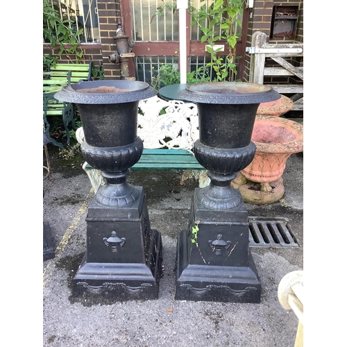 29 - A pair of Victorian style black painted cast iron campana shaped garden urns, on square plinths, dia... 