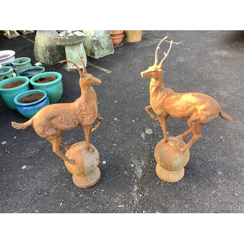 45 - A pair of cast iron finials as deer standing upon spheres, height 92cm. Condition - weathered