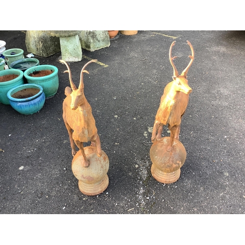 45 - A pair of cast iron finials as deer standing upon spheres, height 92cm. Condition - weathered