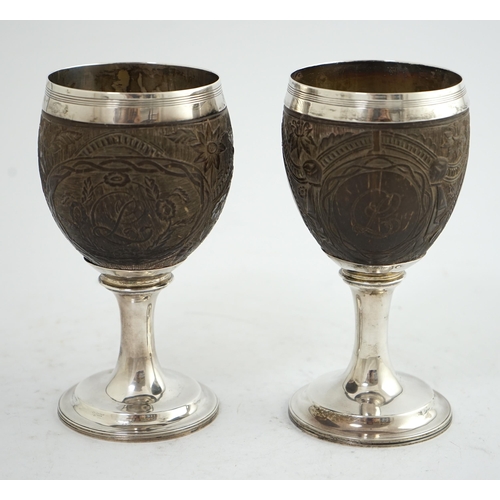 28 - A pair of George III silver mounted coconut cups, maker I.T?, carved with cartouches depicting a pla... 