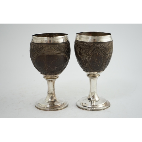 28 - A pair of George III silver mounted coconut cups, maker I.T?, carved with cartouches depicting a pla... 