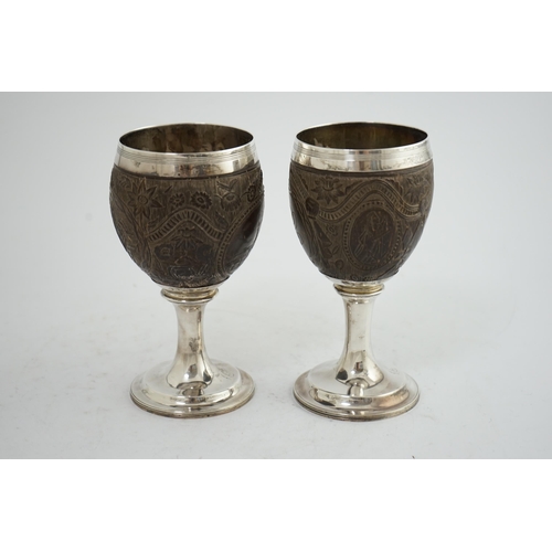 28 - A pair of George III silver mounted coconut cups, maker I.T?, carved with cartouches depicting a pla... 