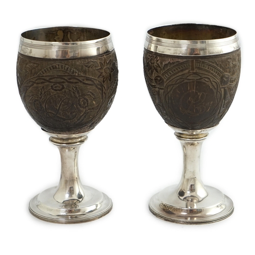 28 - A pair of George III silver mounted coconut cups, maker I.T?, carved with cartouches depicting a pla... 