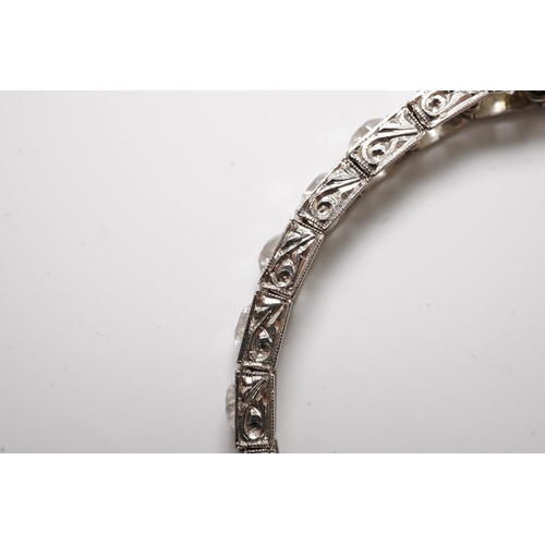 479 - A platinum and thirty one stone round cut diamond set line bracelet, with carved setting, the total ... 