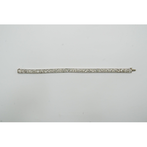 479 - A platinum and thirty one stone round cut diamond set line bracelet, with carved setting, the total ... 