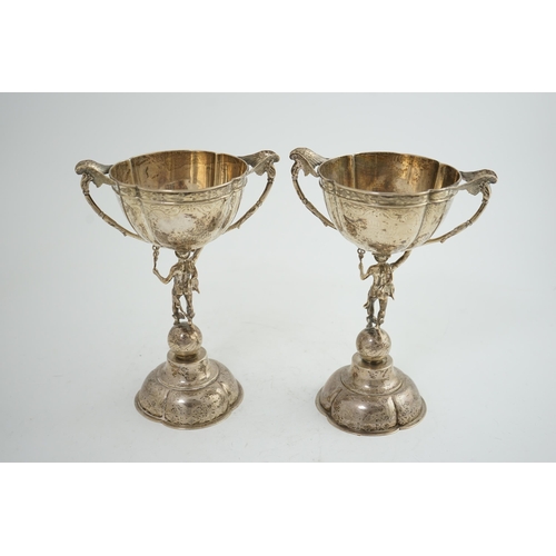 88 - A pair of Victorian silver two handled pedestal cups, each figural stem modelled as Hermes upon a gl... 