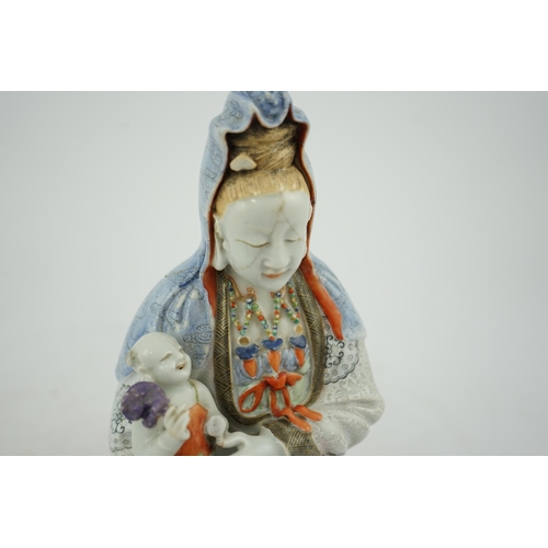 145 - A Chinese enamelled porcelain group of Guanyin holding a child, Qianlong period, seated in lalitasan... 