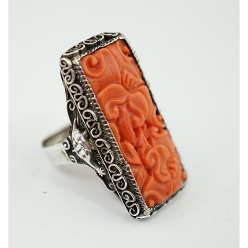 222 - A Chinese carved coral and silver ring, early 20th century, the coral plaque carved and pierced with... 