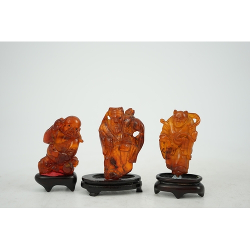 225 - Three Chinese amber figures of immortals, 19th century, each carved in relief and openwork with an i... 