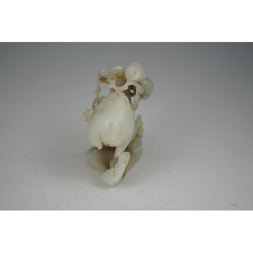 272 - A Chinese white and russet jade figure of a deer, 20th century, the galloping deer grasping a peach ... 