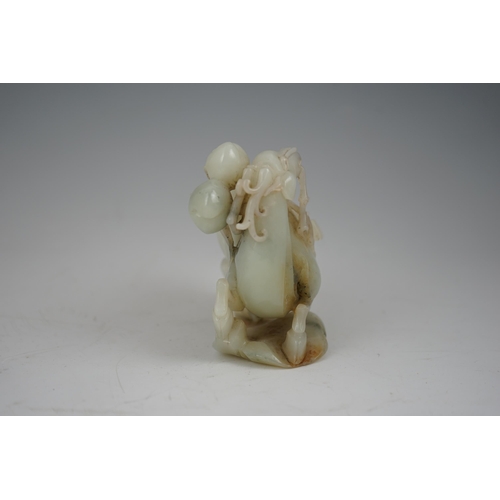 272 - A Chinese white and russet jade figure of a deer, 20th century, the galloping deer grasping a peach ... 