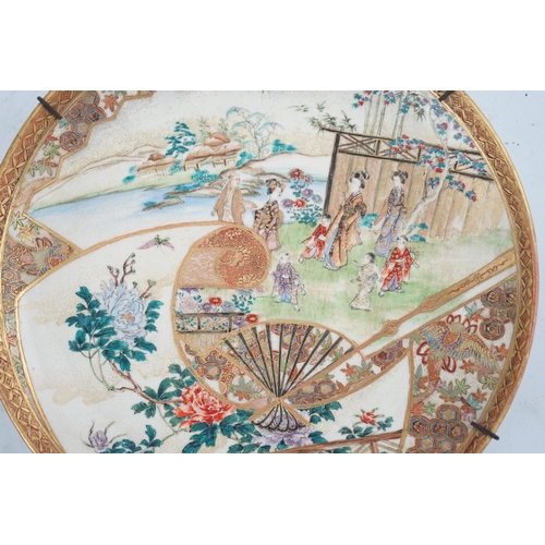 28 - A Japanese Satsuma garden scene dish, Meiji period, painted with figures in a landscape to a fan s... 