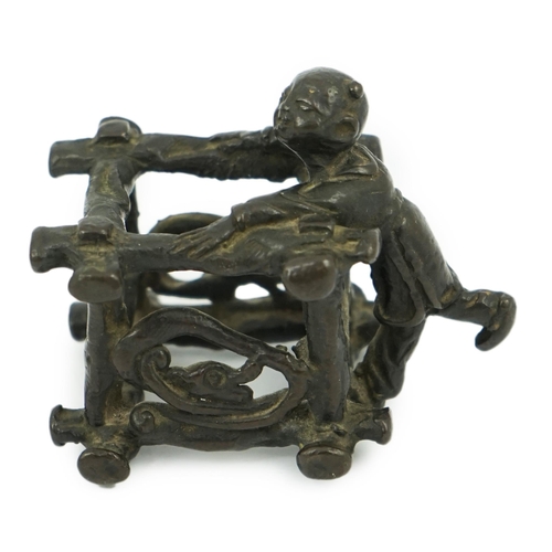 293 - A Chinese bronze figural scroll weight, late Ming, modelled as a boy standing on a wooden frame work... 