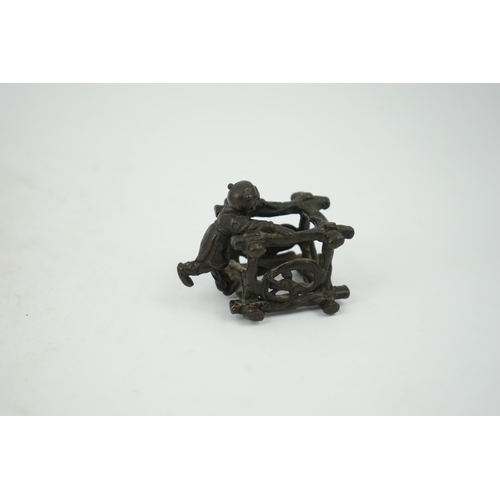 293 - A Chinese bronze figural scroll weight, late Ming, modelled as a boy standing on a wooden frame work... 