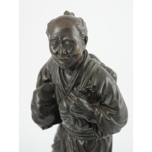 55 - A Japanese bronze figure of a man, 19th century, carrying fabric wrapped packages suspended from str... 